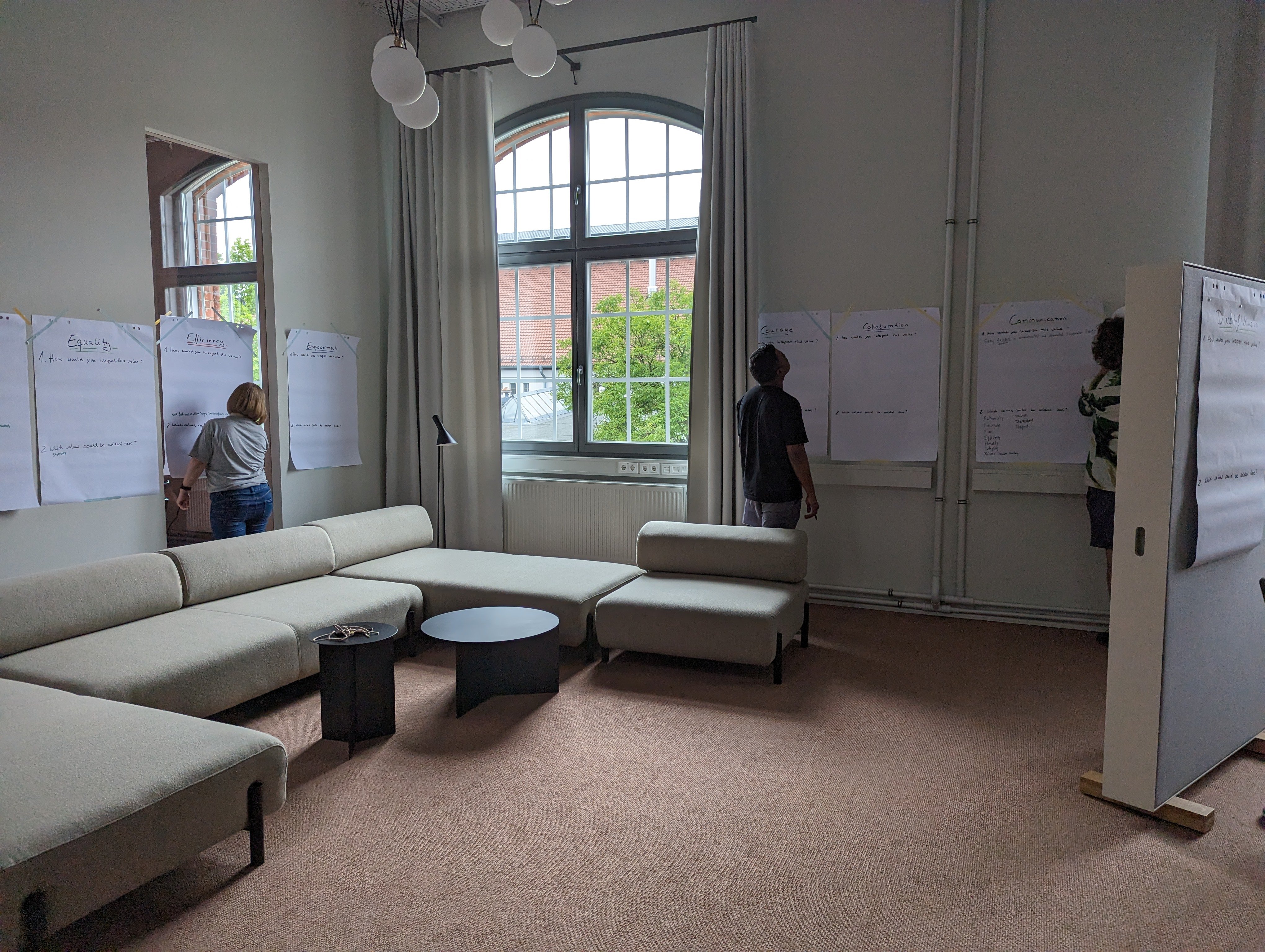 Eine Gruppe von Menschen, die in einem Raum stehen und Plakate bearbeiten im Rahmen eines Workshops