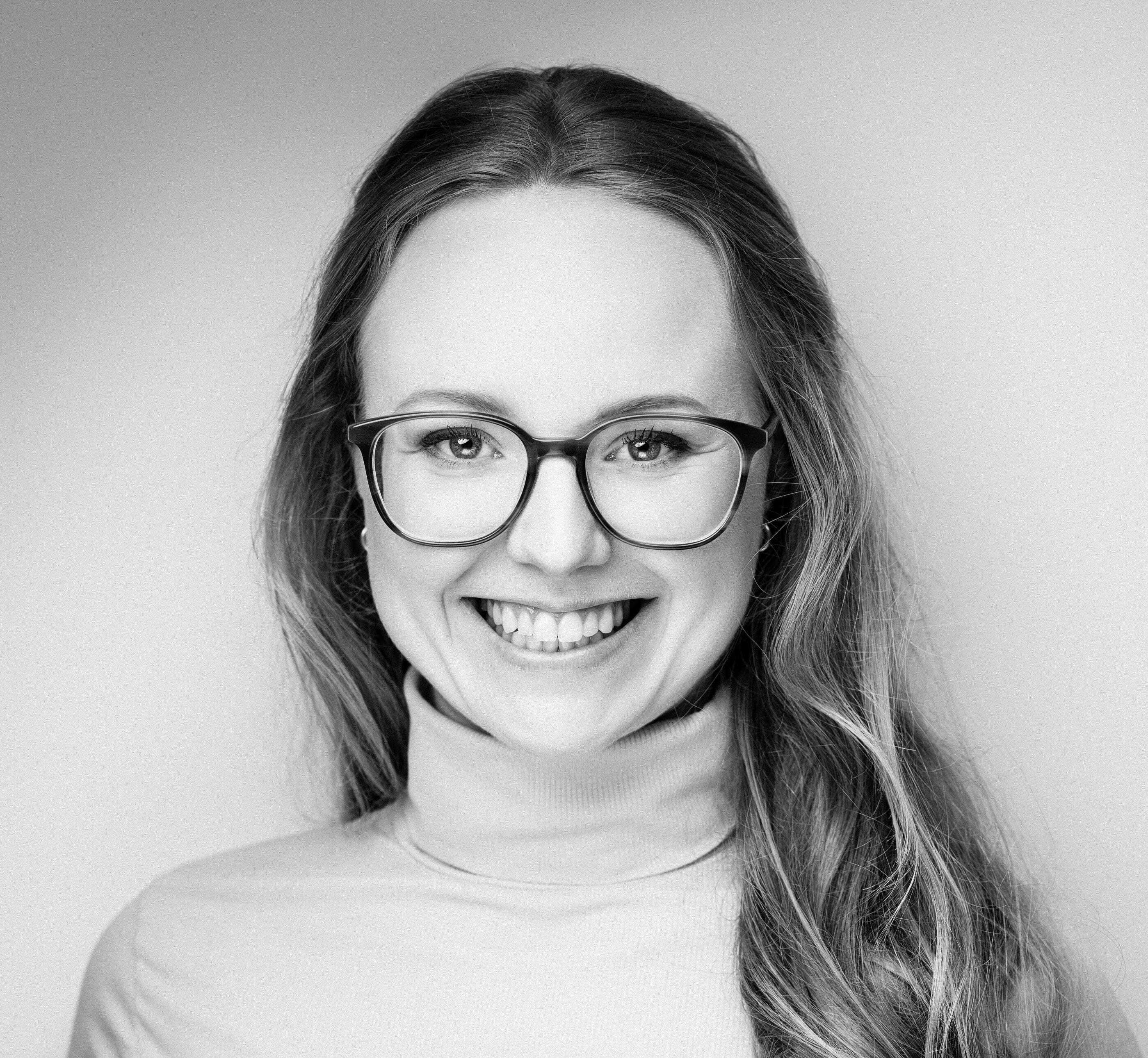 Schwarz weiß Bild einer lächelnde Frau mit langen Haaren und Brille